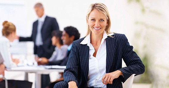 A woman in business attire sitting on top of a chair.